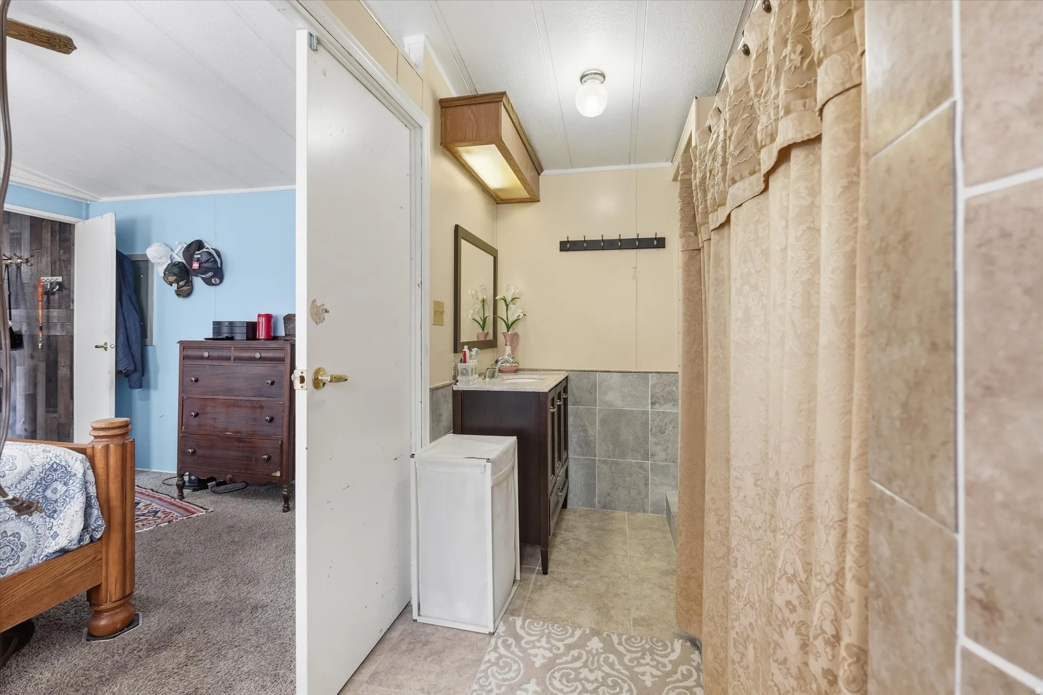 Bathroom featuring a dark wood-finish vanity, wall-mounted mirror, and tile wainscoting