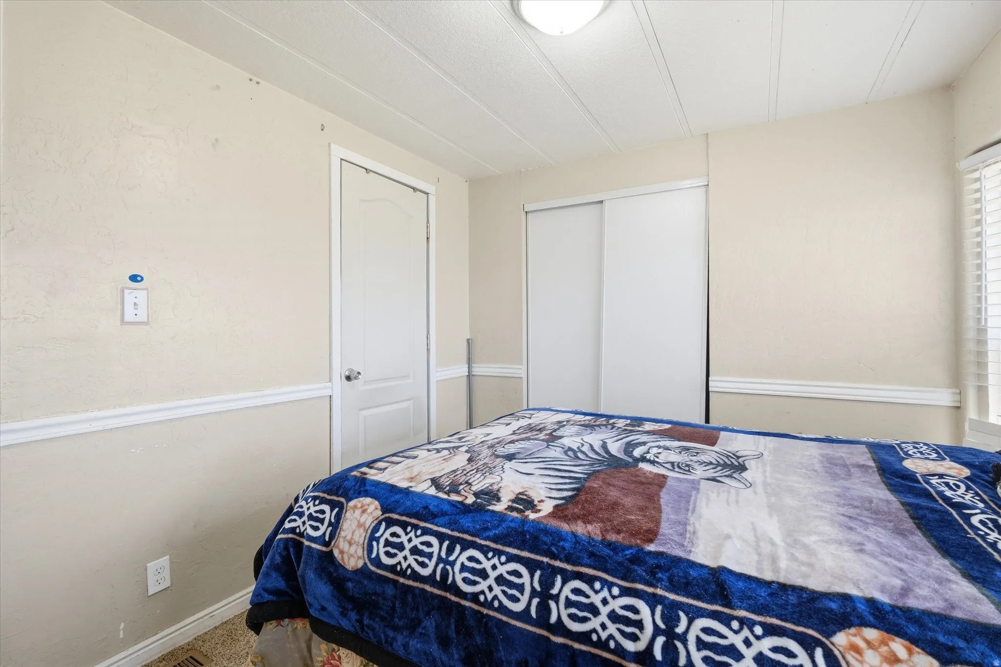 Bedroom featuring neutral-toned walls with chair rail molding, a white paneled door, and a sliding closet