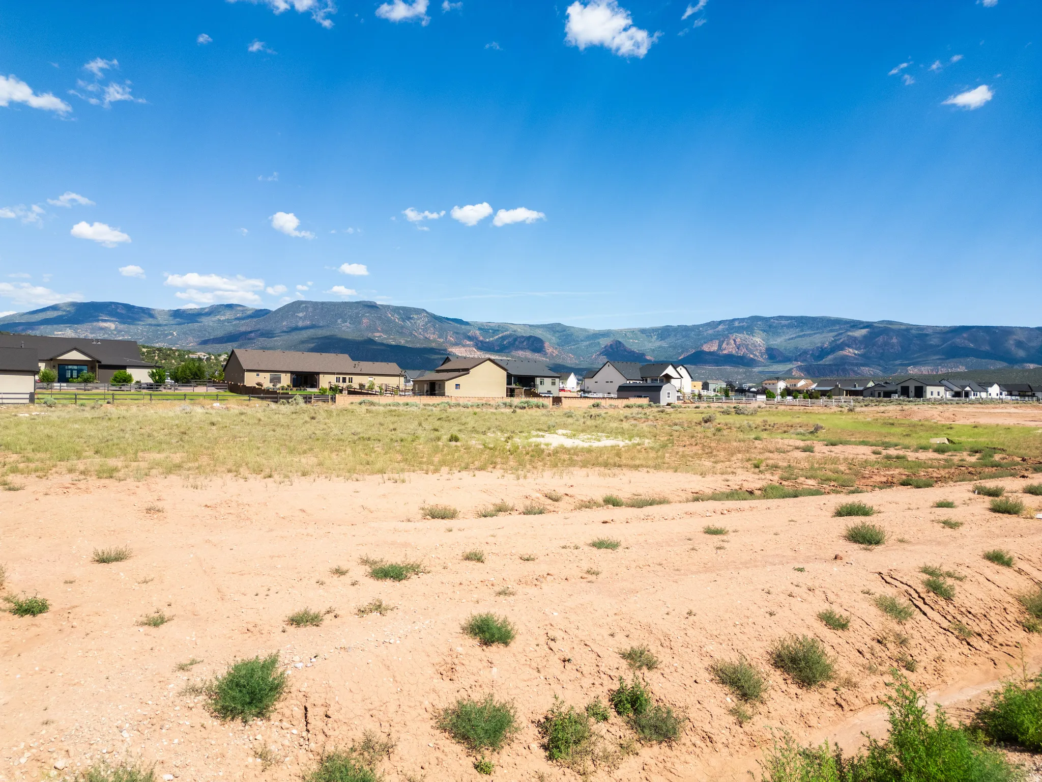 Expansive undeveloped lot featuring sparse ground cover and a distant mountain range backdrop