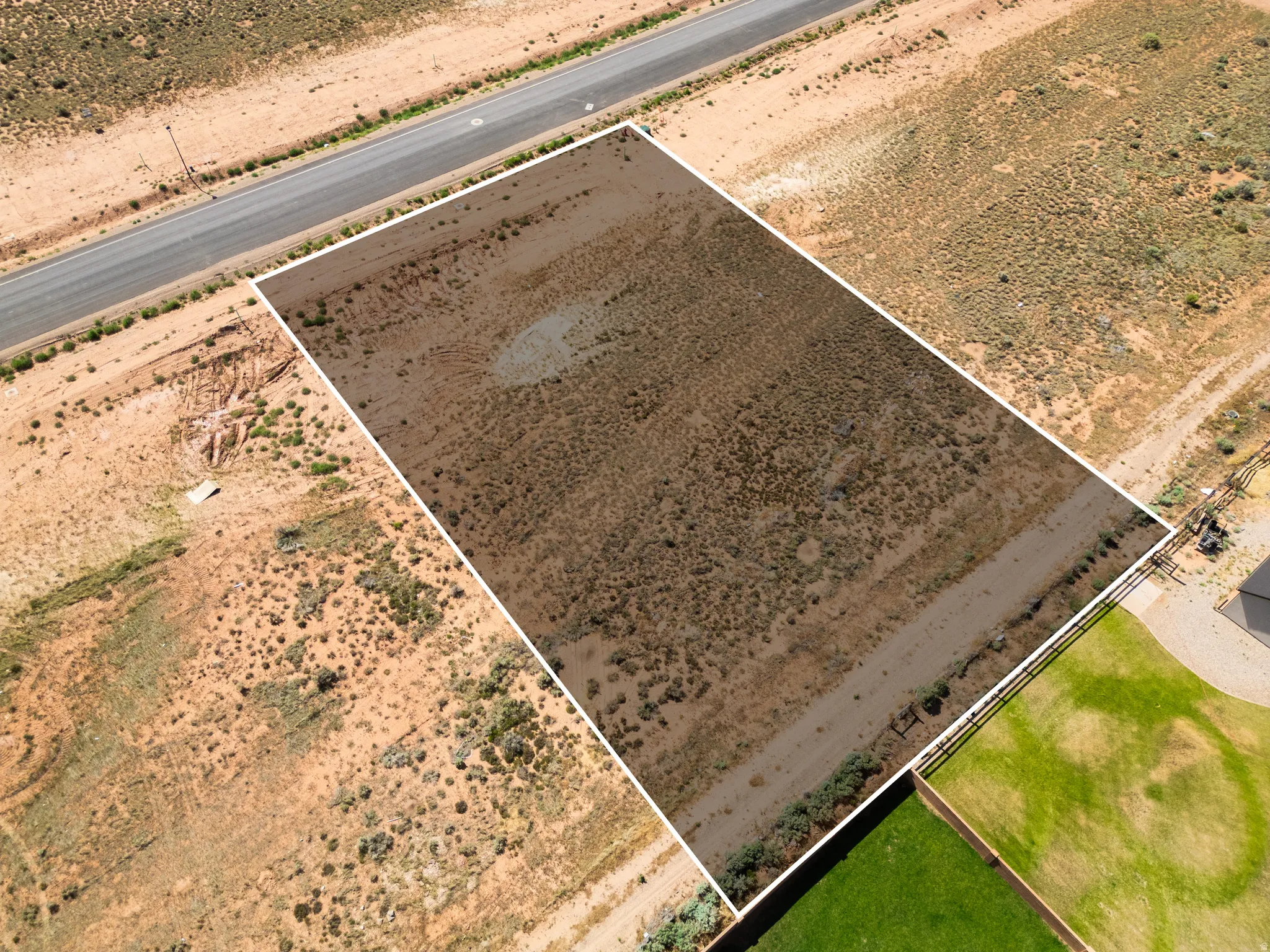 Expansive desert lot featuring natural vegetation, a clear boundary outline, and direct road access