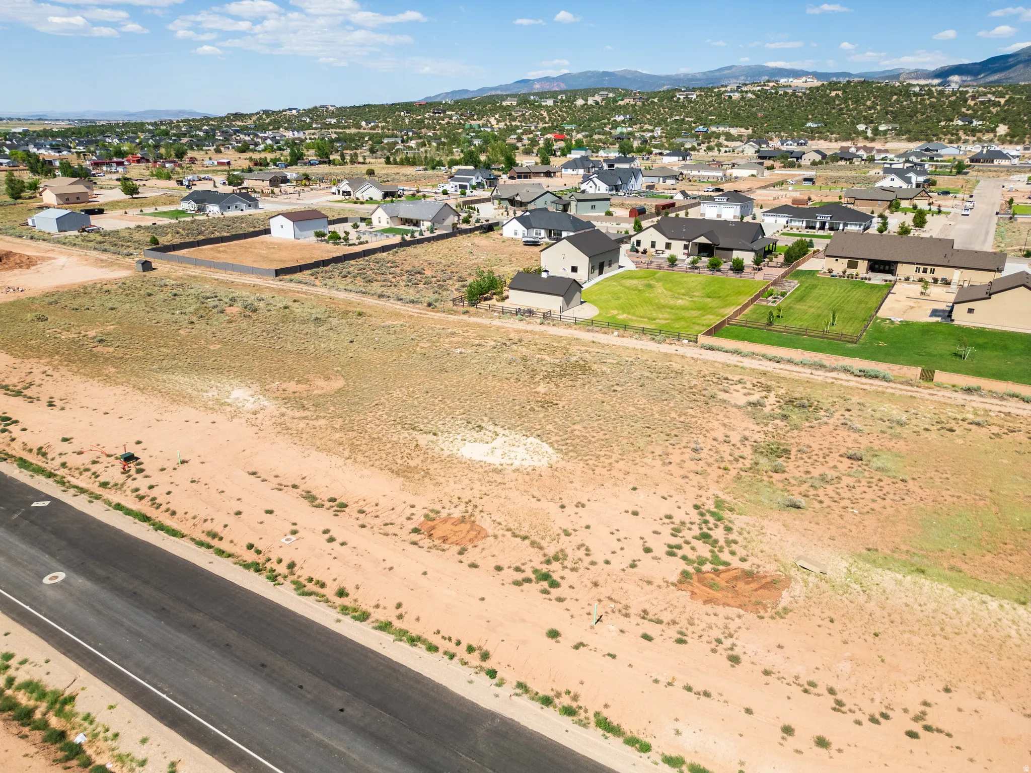 Expansive undeveloped lot featuring a paved road frontage, natural desert landscaping, and distant mountain scenery