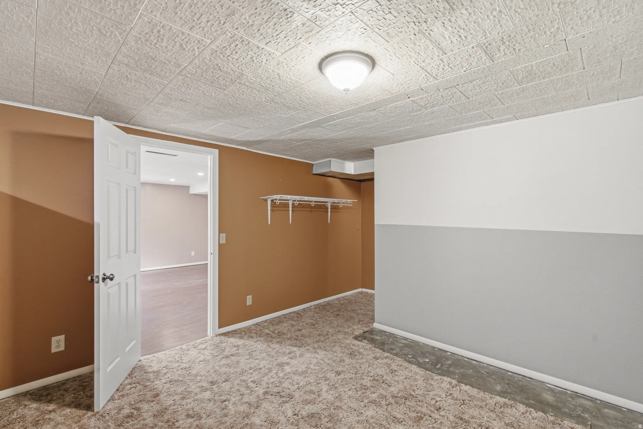 Interior room with textured ceiling tiles, flush-mount lighting, and bi-color painted walls