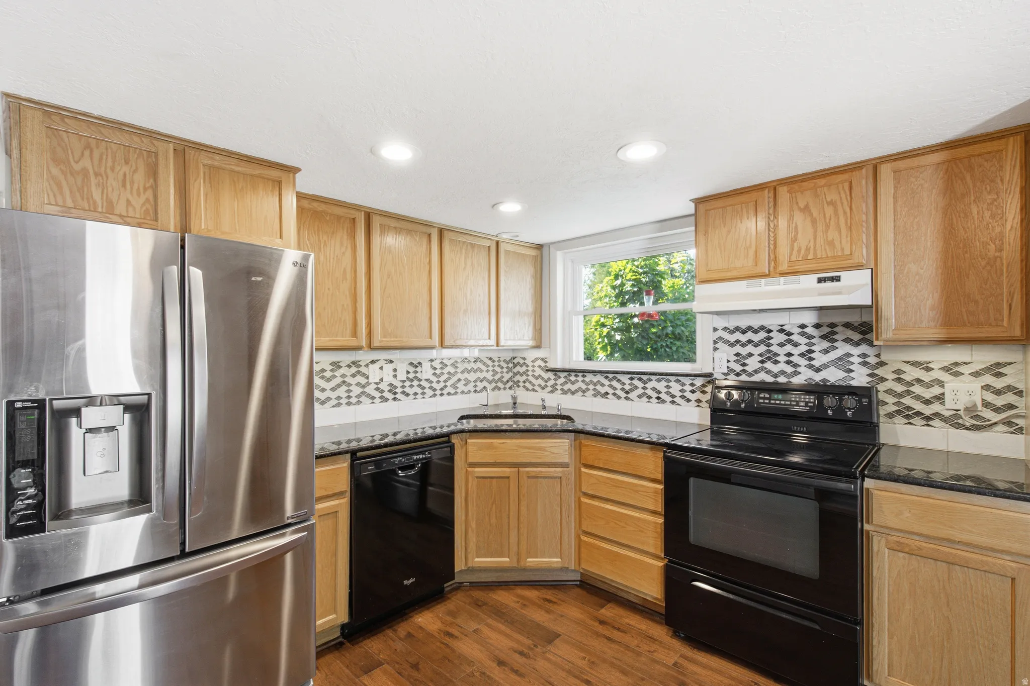 Kitchen featuring wood-finish flooring, recessed lighting, and light wood cabinetry with dark countertops