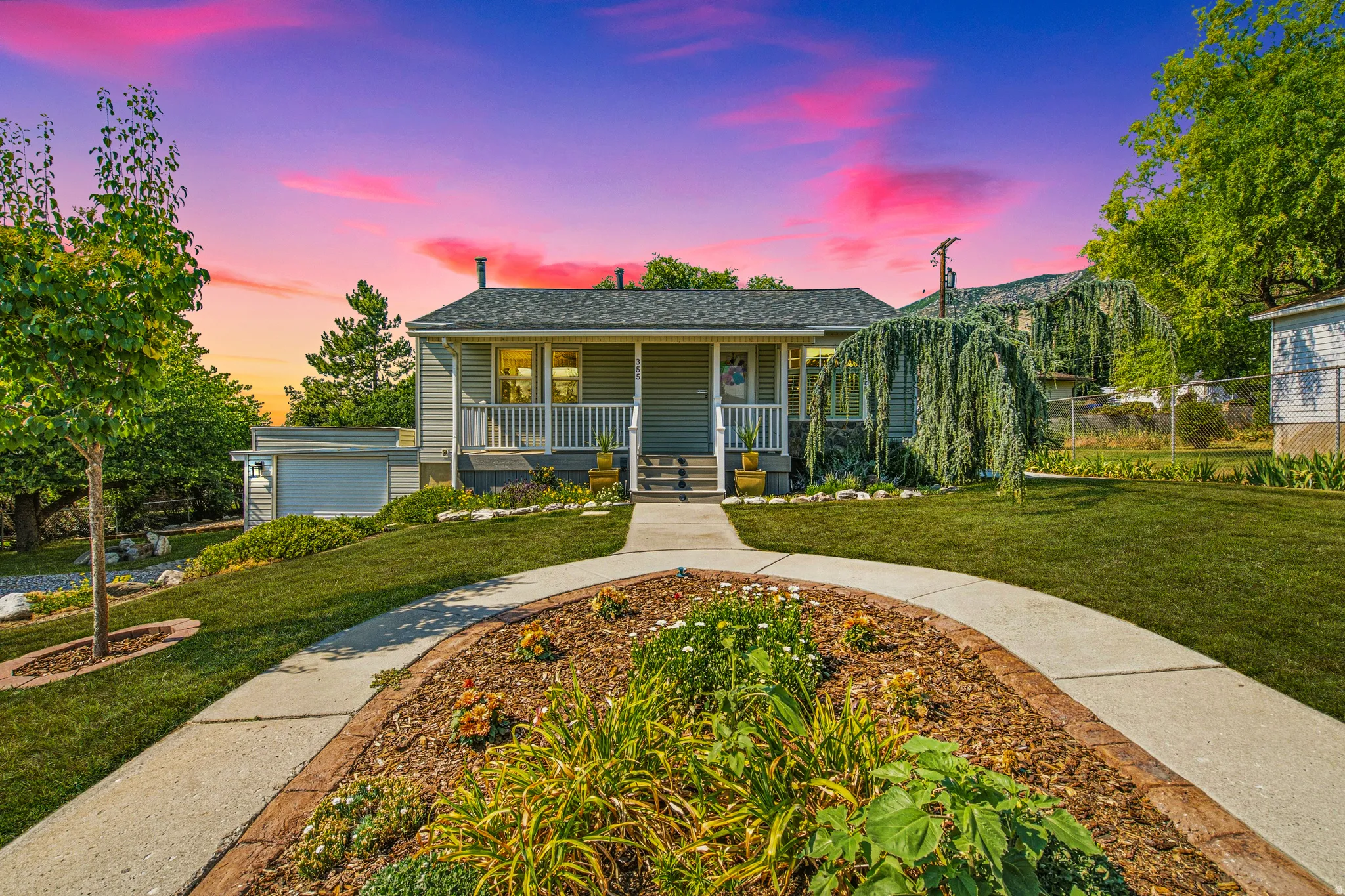 Crafted landscaping with a curved concrete pathway leading to the inviting front porch