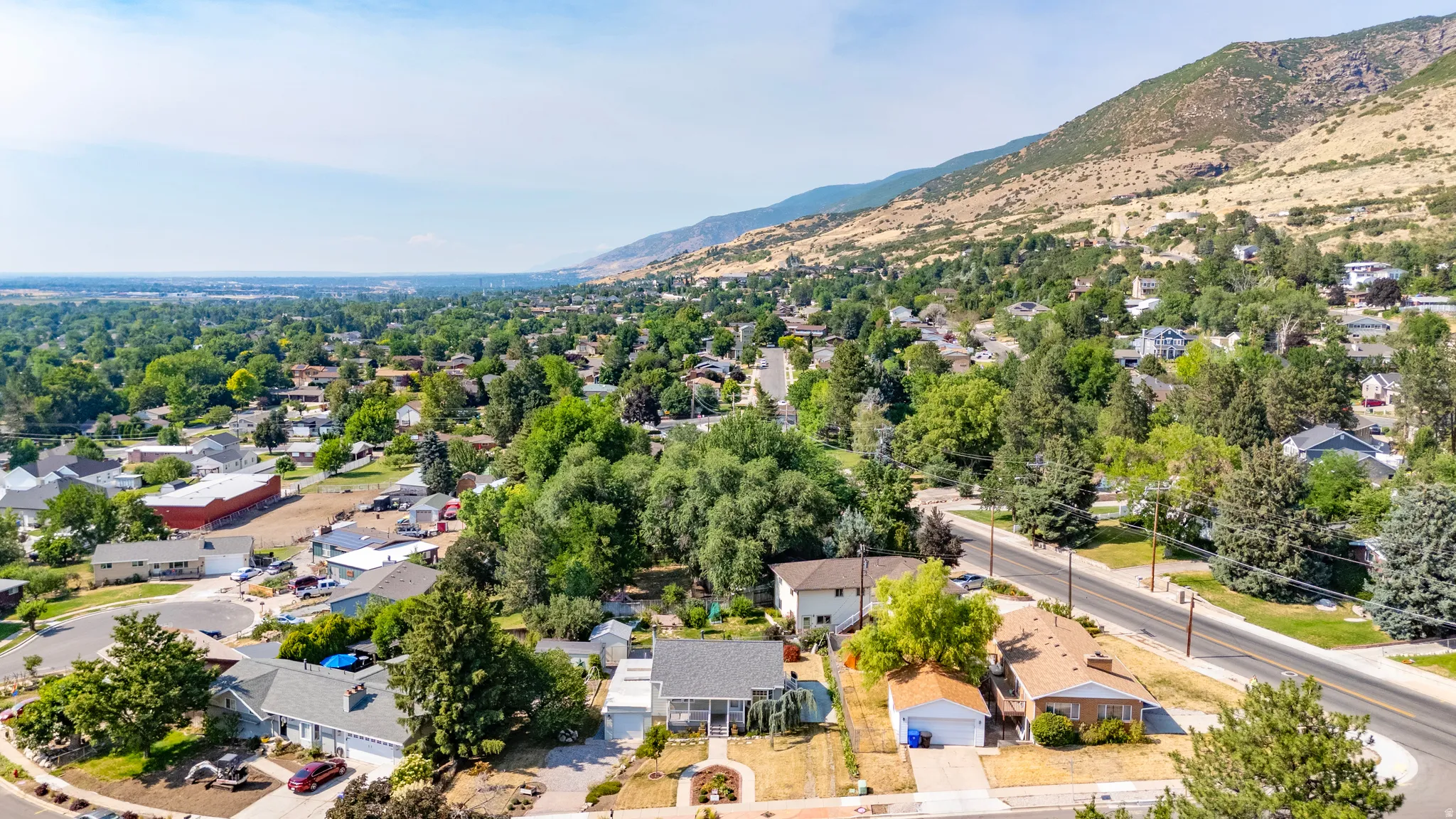 Neighborhood aerial showcasing a prominent mountain backdrop, mature tree canopy, and residential streets