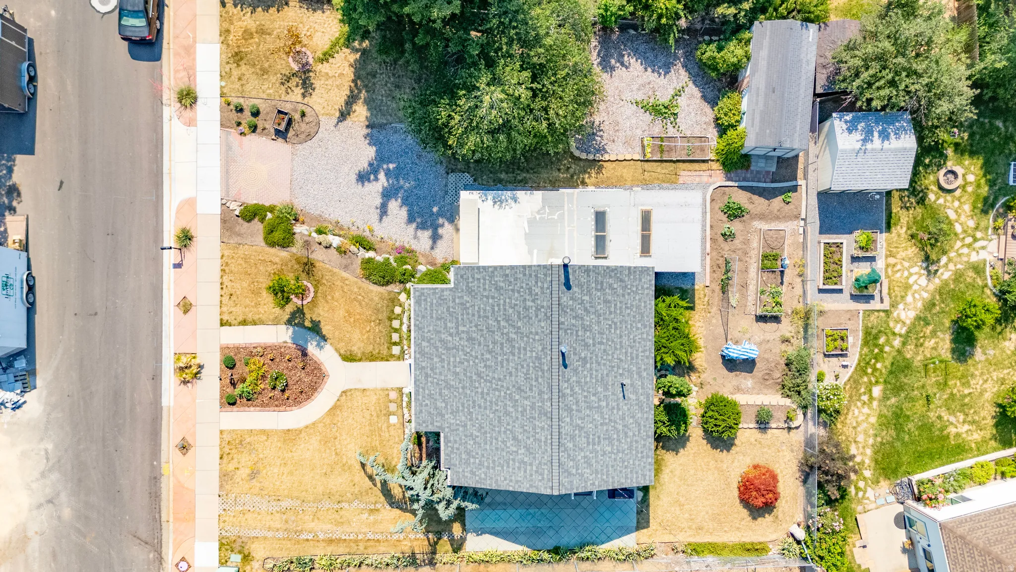 Aerial overview showcasing the property with a gray shingle roof, paved driveway, and established landscaping