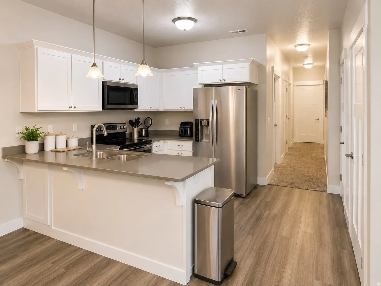 Kitchen featuring white shaker cabinetry, stainless steel appliances, and a peninsula with an undermount sink
