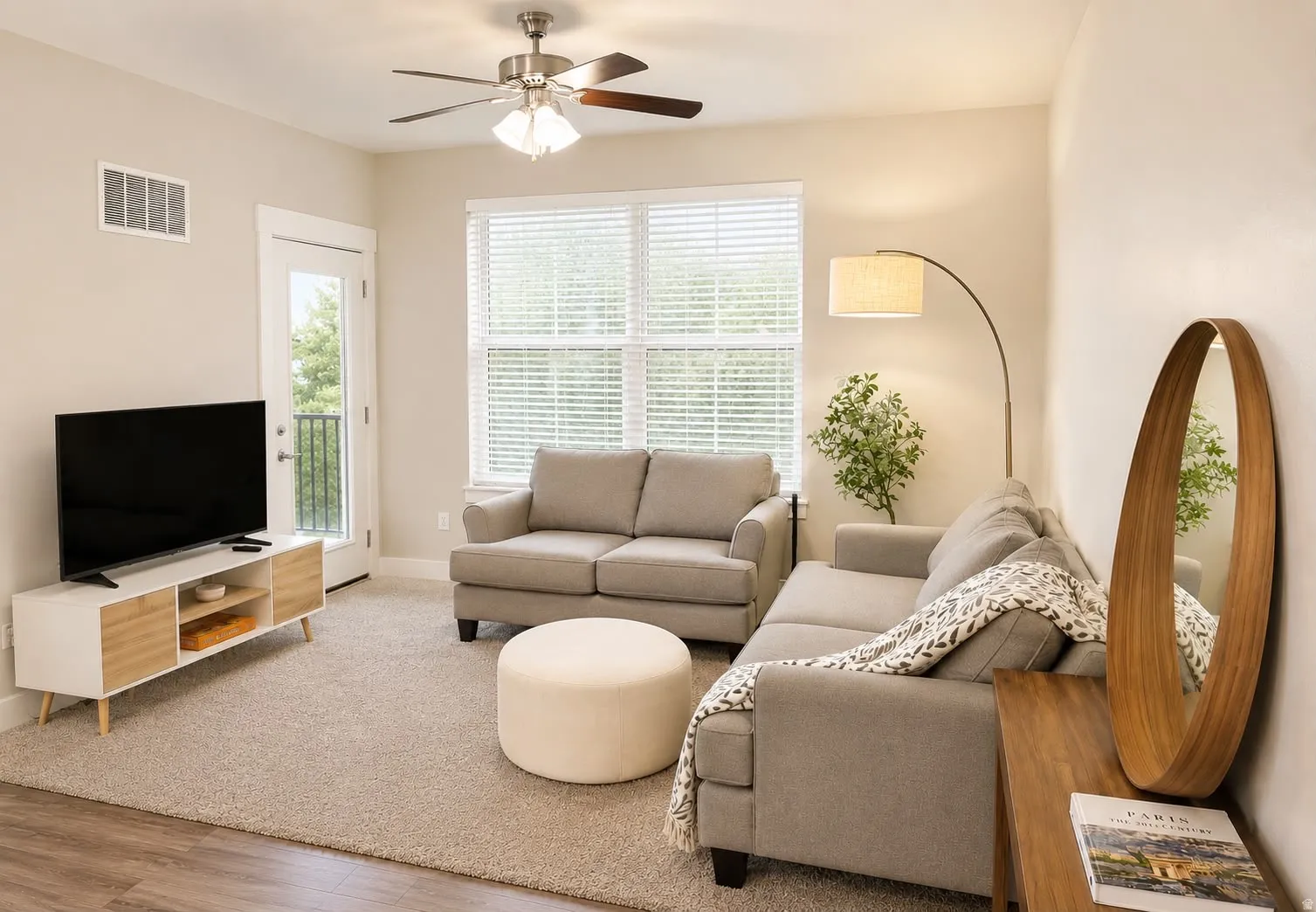 Living area featuring neutral-toned carpet flooring, a ceiling fan with integrated lighting, and a white door leading to an outdoor space