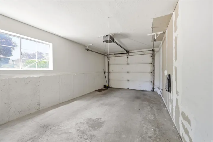 Spacious garage featuring a concrete floor, overhead garage door with opener, and a large window providing natural light