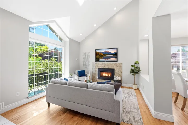 Living area featuring vaulted ceilings, recessed lighting, and wood-finish flooring