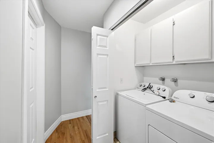 Dedicated laundry area featuring a washer and dryer, overhead cabinetry, and light-toned walls