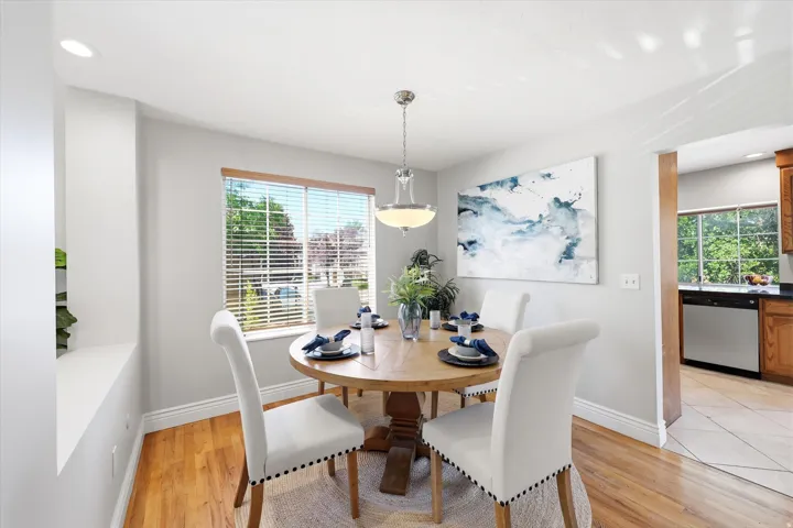 Dining area featuring wood-finish flooring, recessed lighting, and a prominent window with horizontal blinds