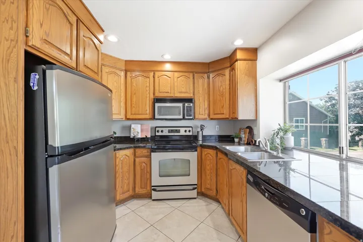 Kitchen with ample wood cabinetry, dark countertops, and tile flooring