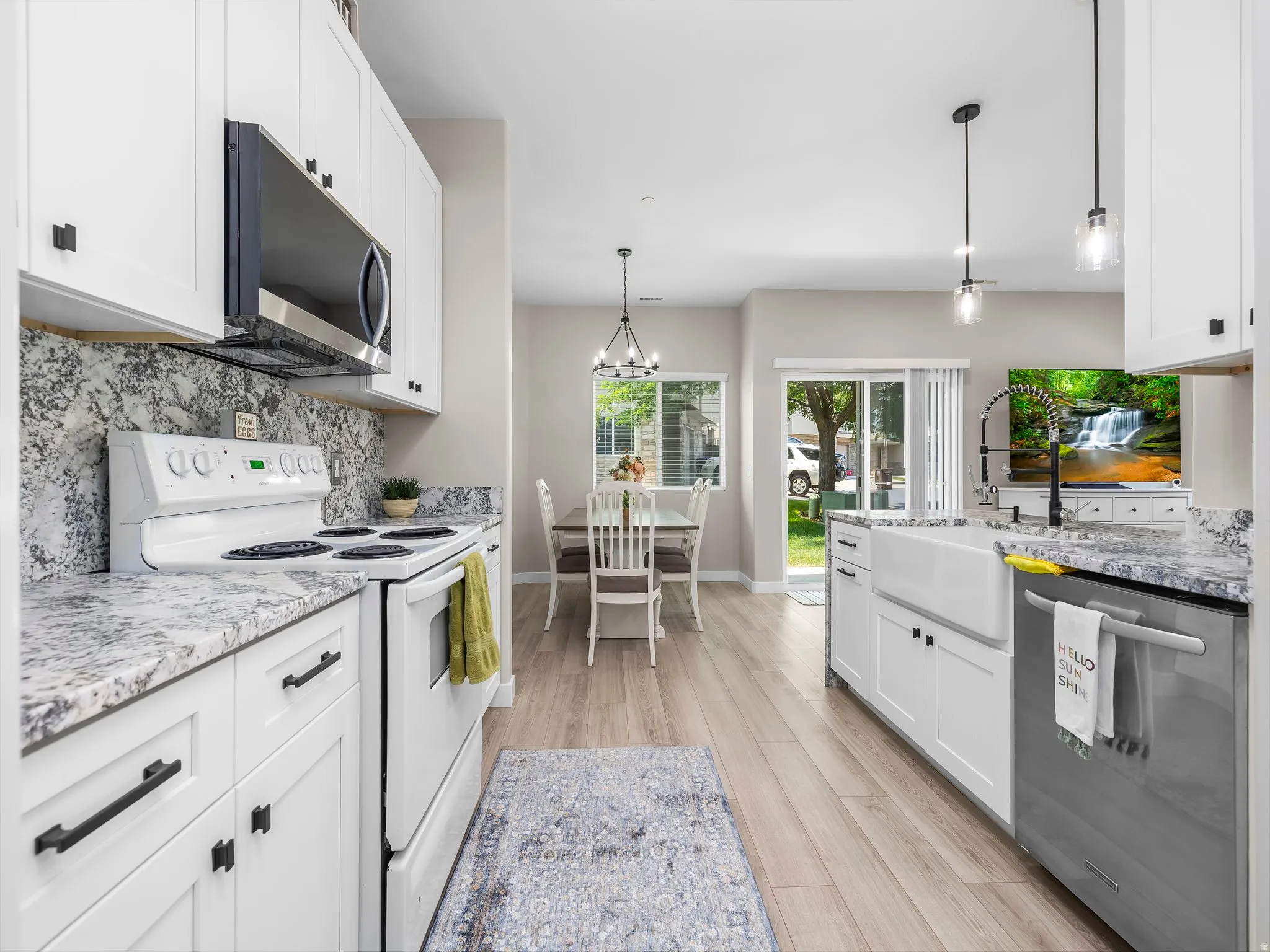 Kitchen featuring white cabinetry, light-toned wood-finish flooring, and light-colored countertops with a textured backsplash