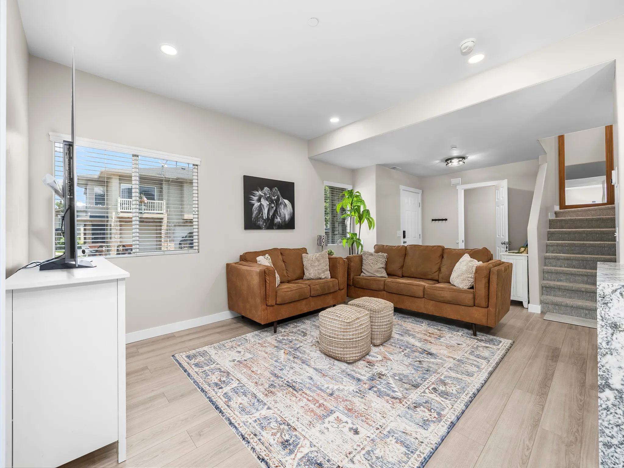 Bright living area featuring light wood-finish flooring, recessed lighting, and a window with horizontal blinds