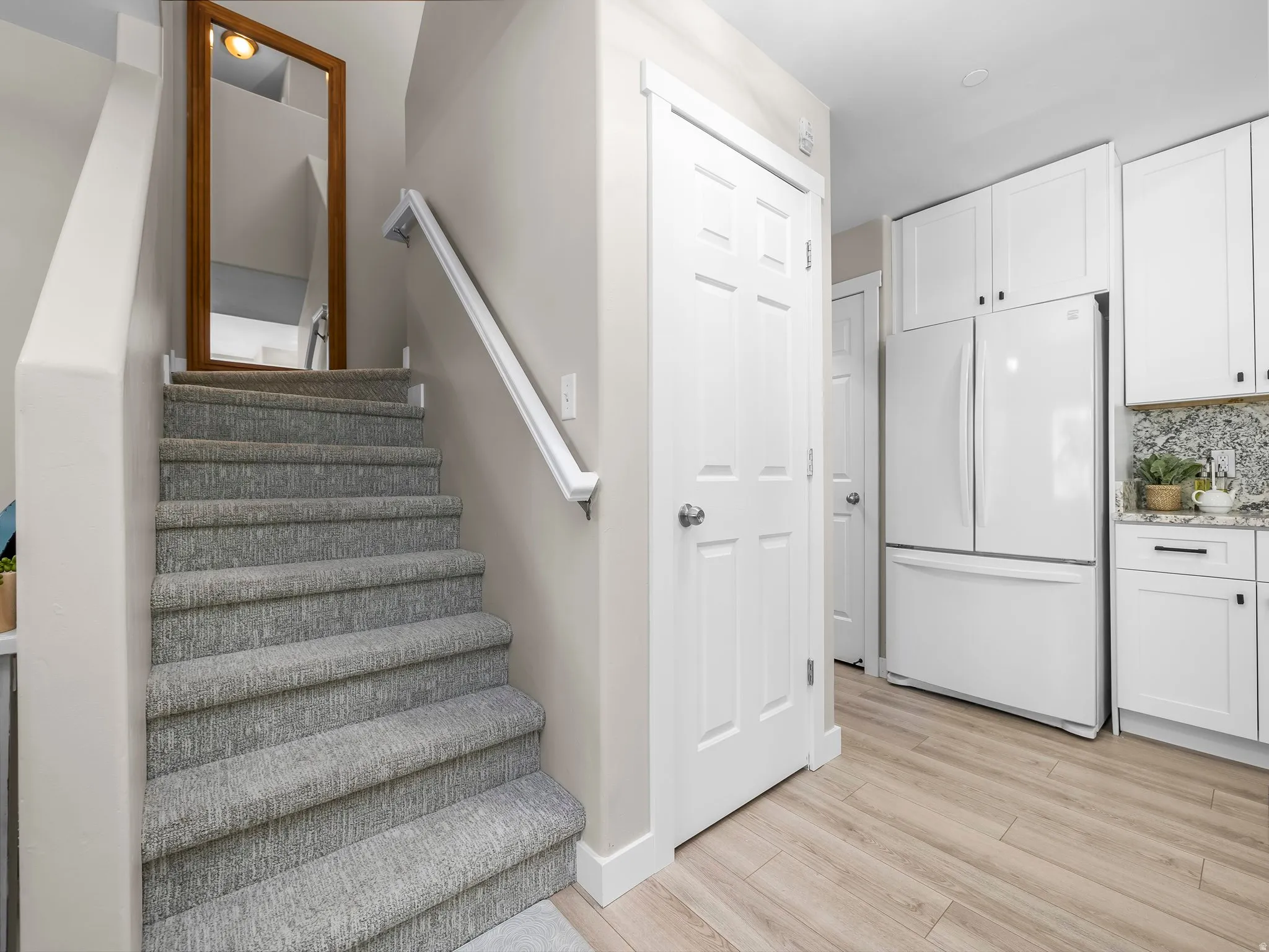 Staircase featuring light gray carpeted treads and a white handrail