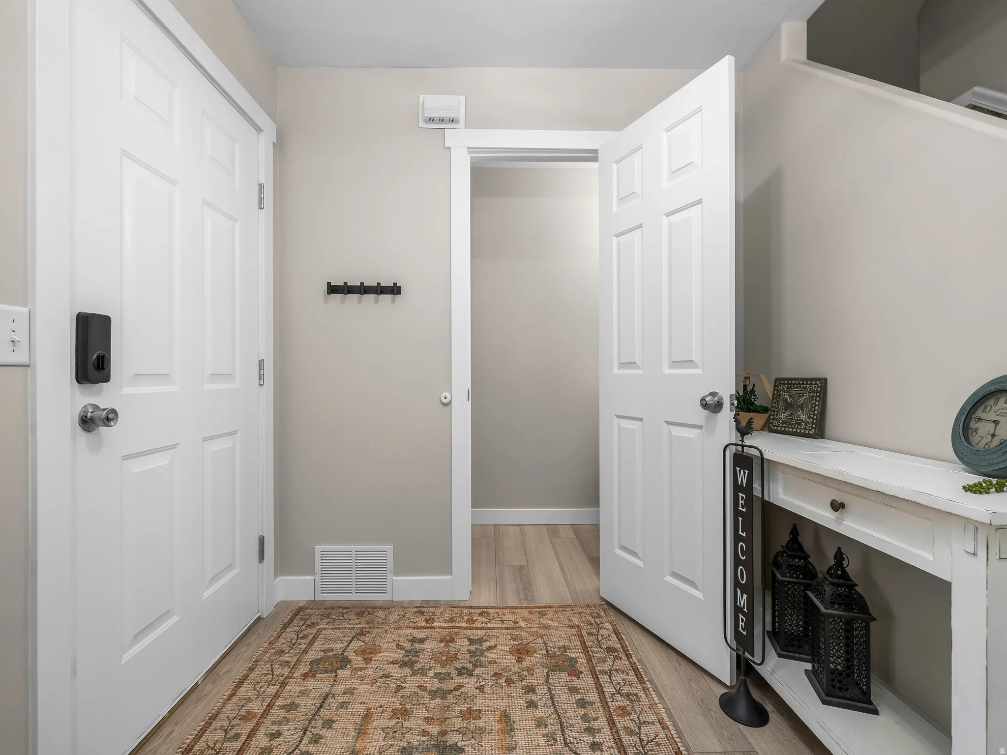 Foyer featuring wood-finish flooring, light-toned walls, white trim, and a white panel door with modern hardware
