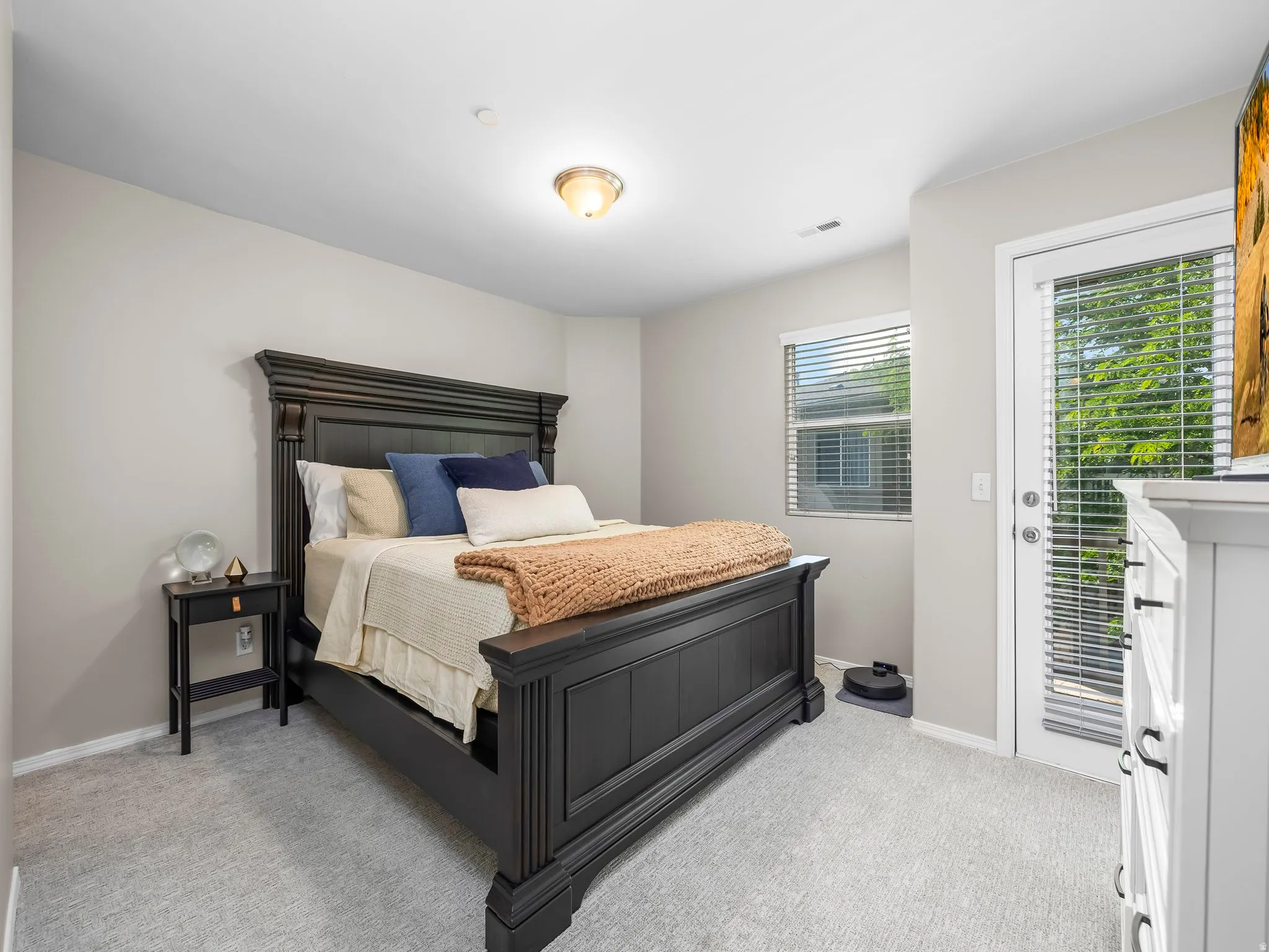 Carpeted room featuring a ceiling-mounted light fixture, a window with horizontal blinds, and a white door with full-length glass panels