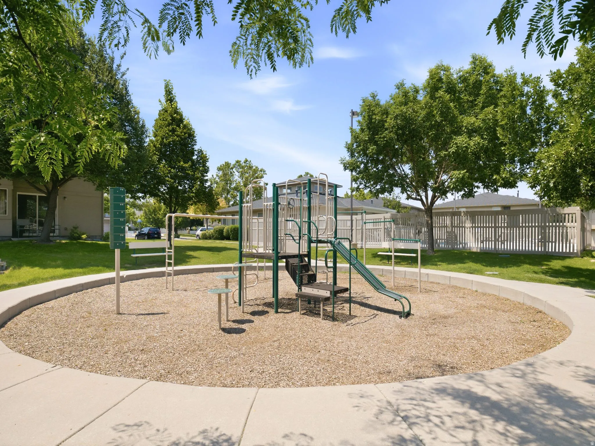 Community playground featuring a multi-level play structure with a slide, surrounded by wood chips