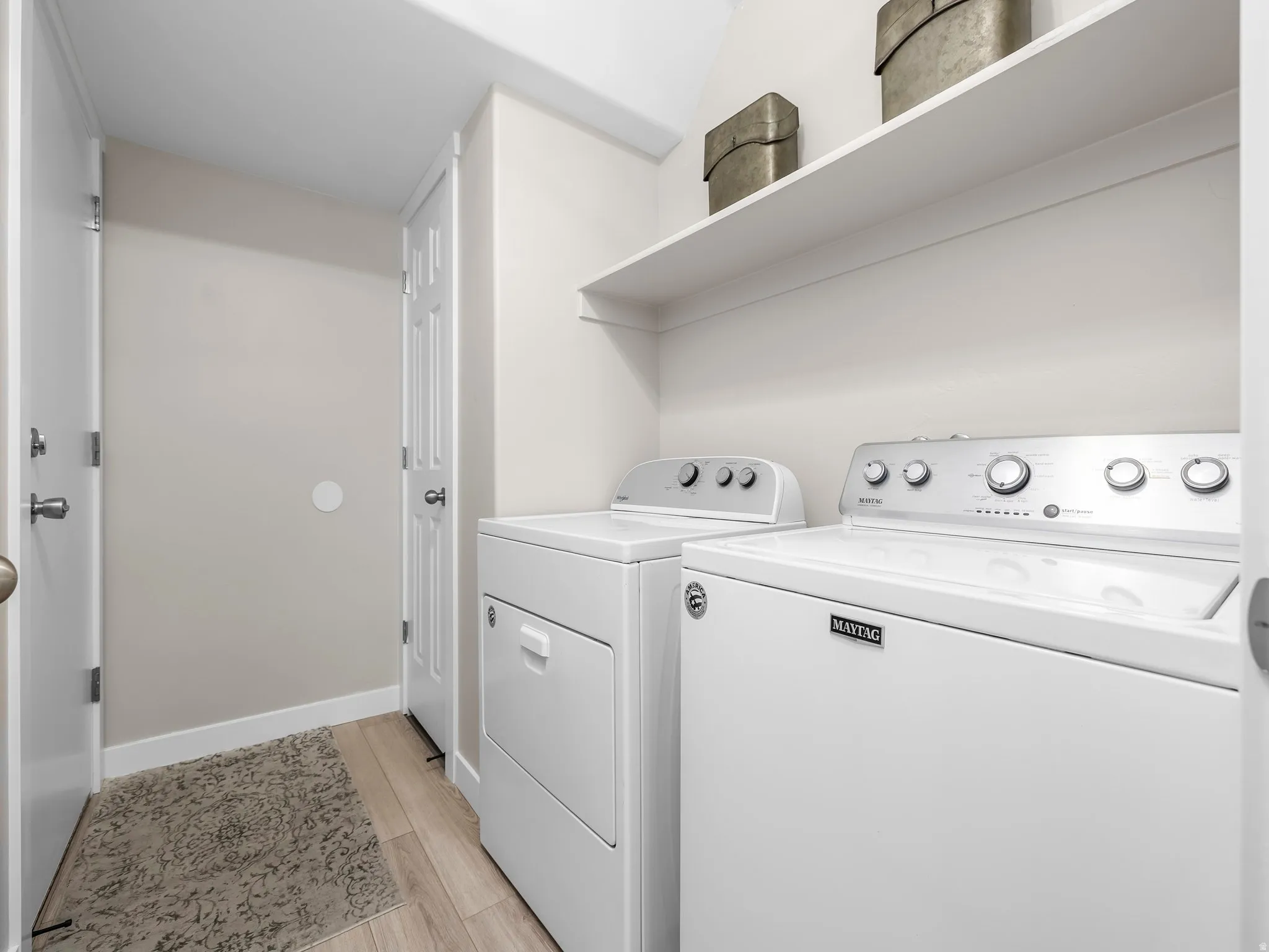 Dedicated laundry area featuring a washer and dryer, wood-finish flooring, and an integrated wall shelf