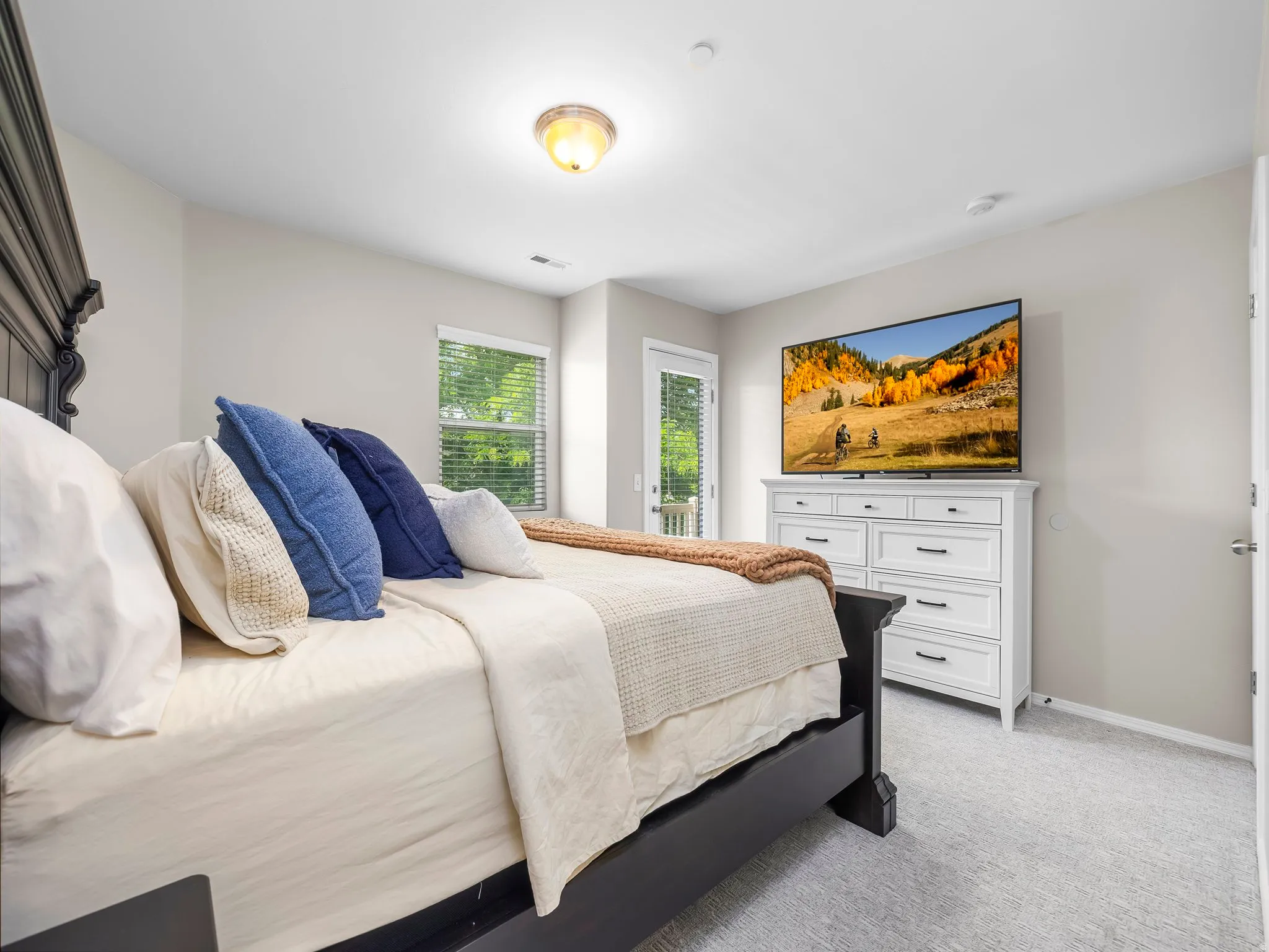 Carpeted bedroom with a vaulted ceiling and a ceiling-mounted light fixture