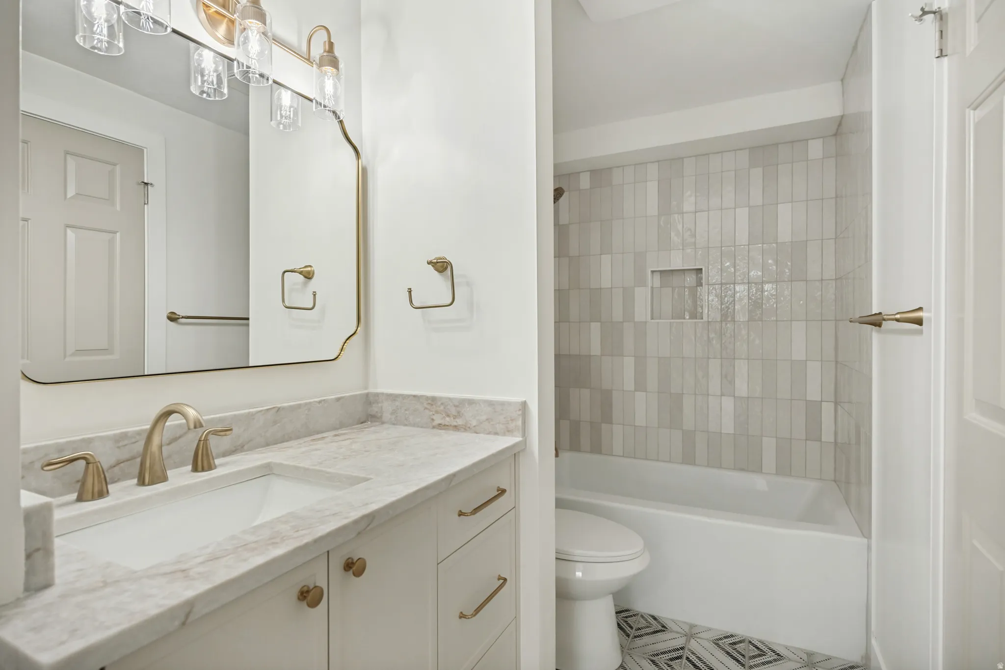 Bathroom featuring a single vanity with a white rectangular sink, a light-toned countertop, and gold-finish fixtures