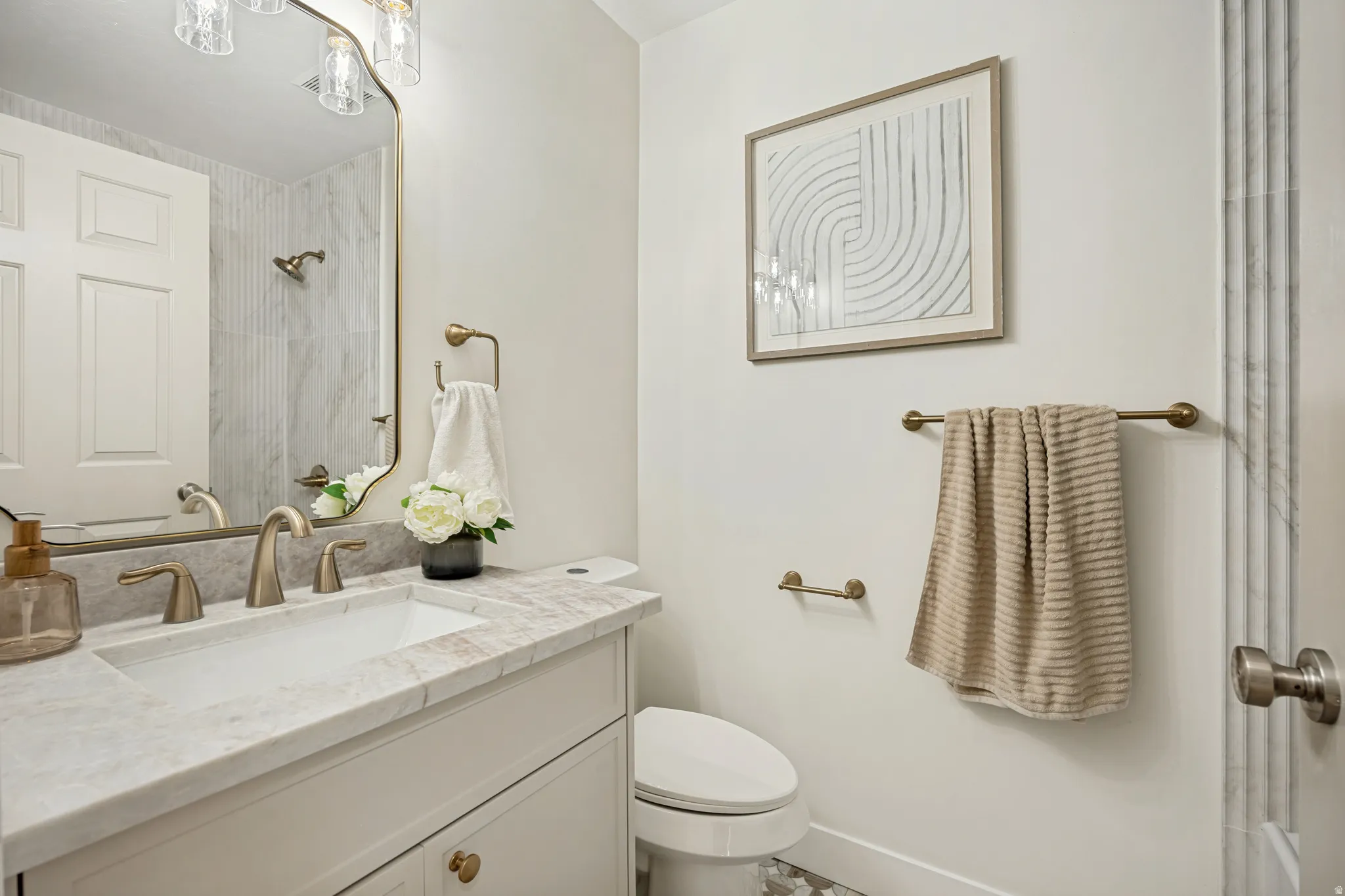 Modern bathroom featuring a white vanity with an integrated sink, stone-finish countertop, and brushed brass fixtures