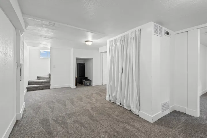 Spacious interior room with gray carpet and white walls