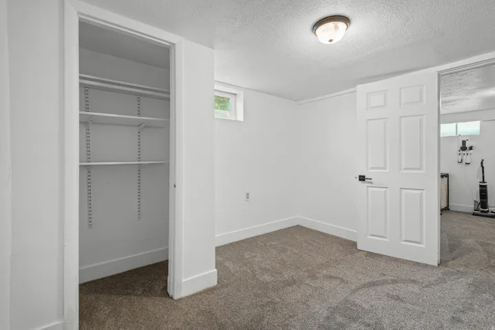 Room featuring neutral-tone carpeting, white walls, and a window for natural light