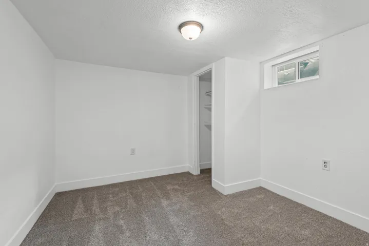 Compact room featuring gray carpeting, white walls, and a single window