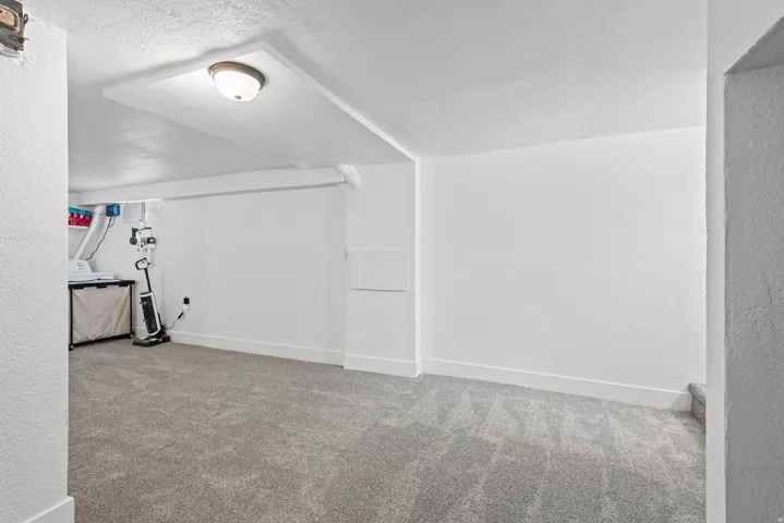 Spacious room featuring new gray carpet, white painted walls, and a flush-mount ceiling light fixture
