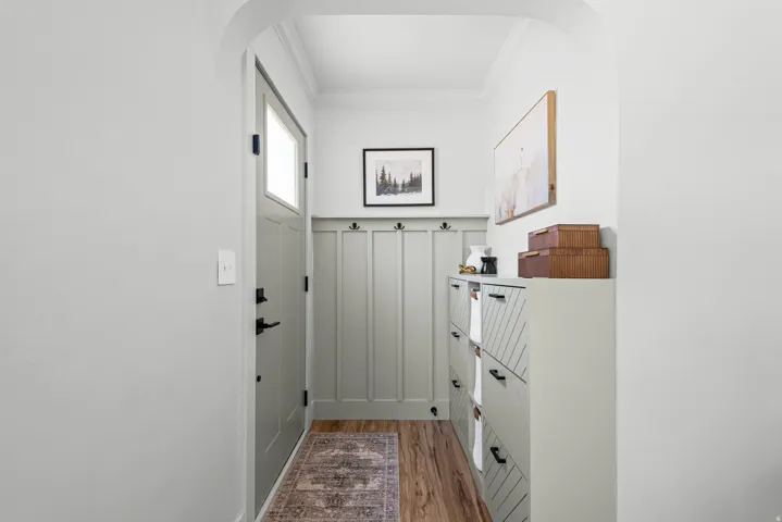 Entryway featuring wood-finish flooring, a light gray door with window pane, and board and batten paneling