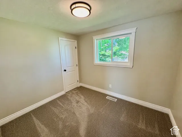 Bedroom featuring neutral-toned walls, plush carpeting, and a white paneled door