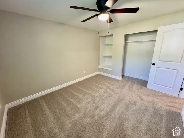 Neutral-toned carpeting in this room featuring a ceiling fan with integrated lighting