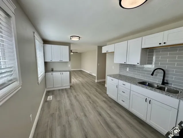 Kitchen featuring white shaker-style cabinetry, a double basin sink with a matte black faucet, and a subway tile backsplash