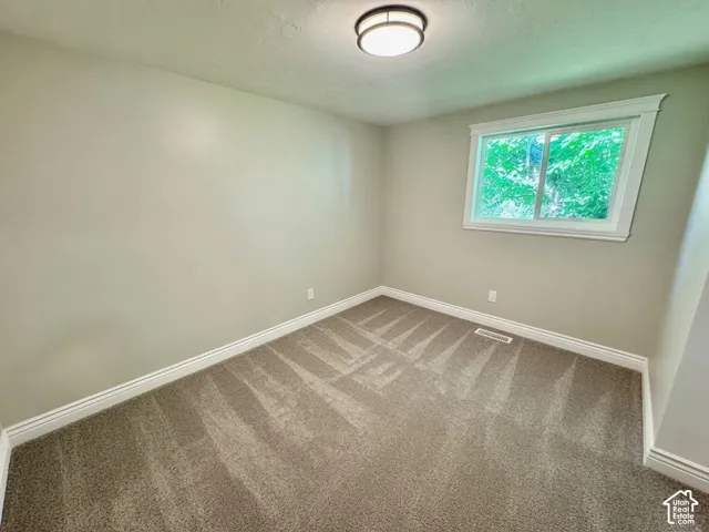 Room featuring neutral wall paint, carpet flooring, and a single window with white trim