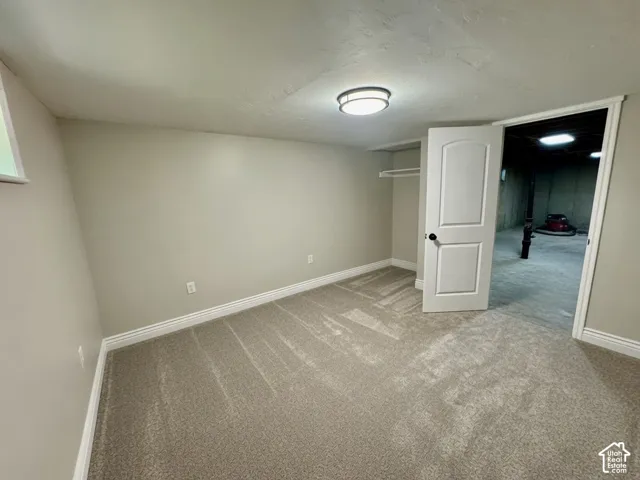 Neutral-toned room featuring a single window, overhead flush mount light fixture, textured ceiling, and light gray carpet flooring
