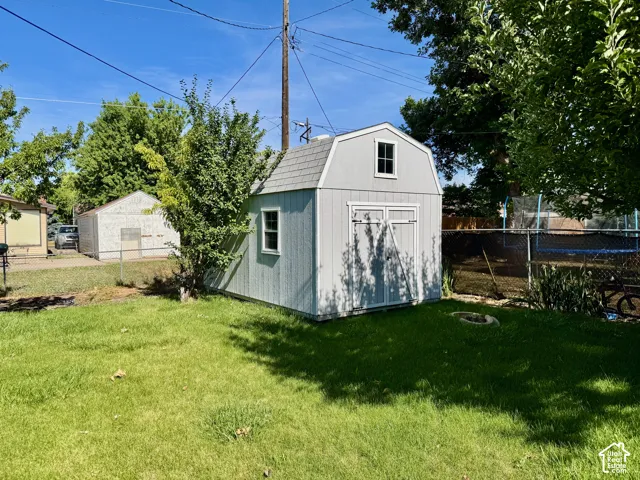 Storage shed with light gray siding, white trim, and a gambrel roof