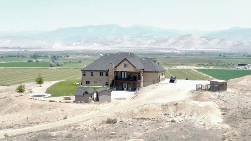 Expansive property featuring a multi-story residence with a dark shingle roof and stone/stucco exterior