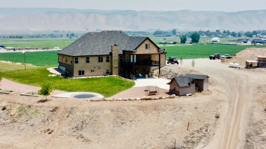 Multi-level residence featuring a dark shingle roof, light-toned exterior siding, and a stone chimney