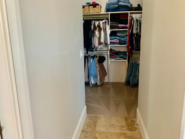 Walk-in closet featuring built-in shelving, multiple hanging rods, and an organized storage system