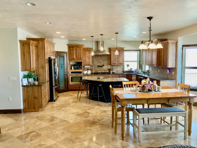 Spacious kitchen featuring extensive cabinetry, an island with seating, stainless steel appliances, and stone tile flooring