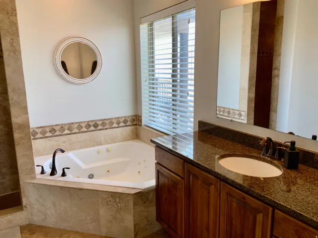 Corner jetted tub set within a tiled surround, featuring oil-rubbed bronze fixtures