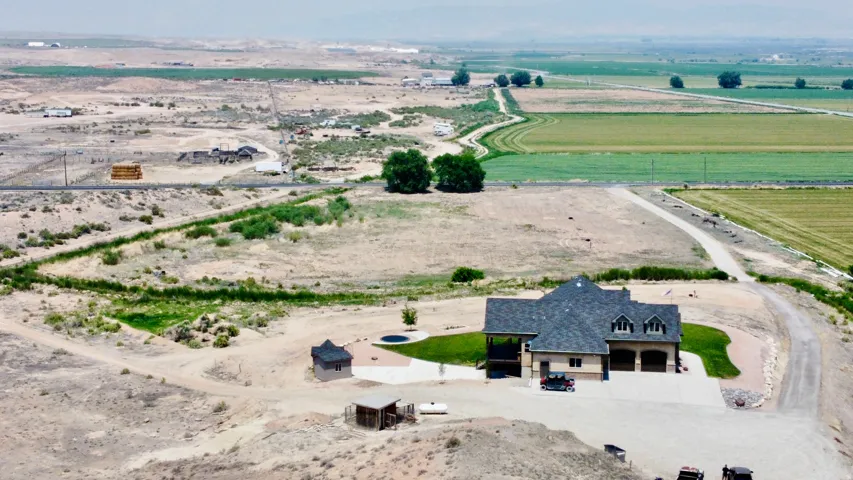 Custom residence featuring a paved driveway, two-car garage, and a covered patio