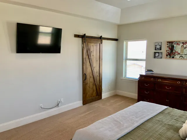 Wood-finish barn door entry featuring a dark metal track