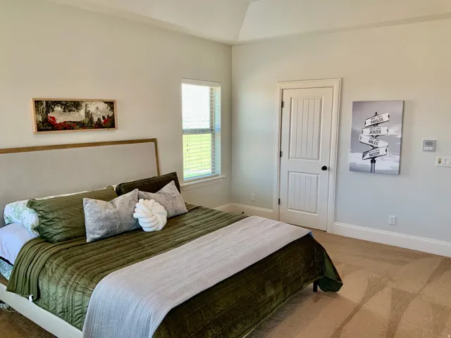 Recessed ceiling with layered trim, framed window with blinds, paneled interior door with dark hardware, and light-toned carpeting