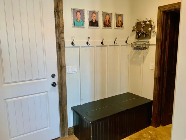 Entryway featuring white vertical paneling and a dark wood-finish bench with integrated storage