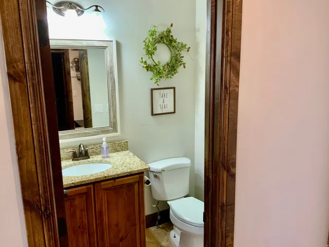 Bathroom featuring a wood-framed mirror, two-light vanity fixture, granite-style countertop, and wood-finish cabinetry
