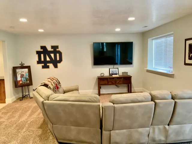 Recessed lighting illuminates a spacious room featuring light-colored walls and plush carpeting