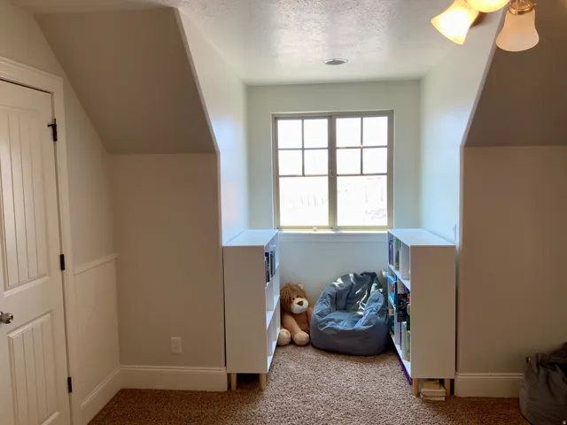 Bright window nook featuring a multi-pane window, sloped ceiling details, a paneled door, and built-in shelving